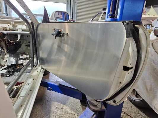 Car door with a metal panel on a car lift in a garage setting