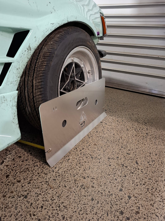 Metal plate propped against wheel of car in a workshop setting