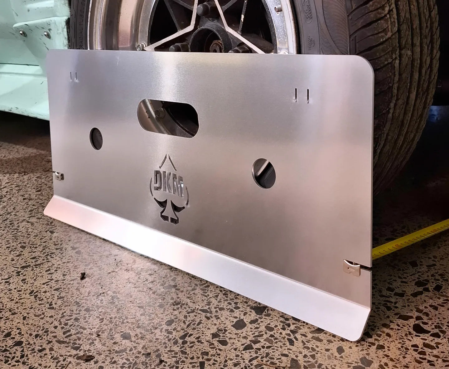 dkm in-house products - toe alignment plate rested against wheel of car in workshop setting
